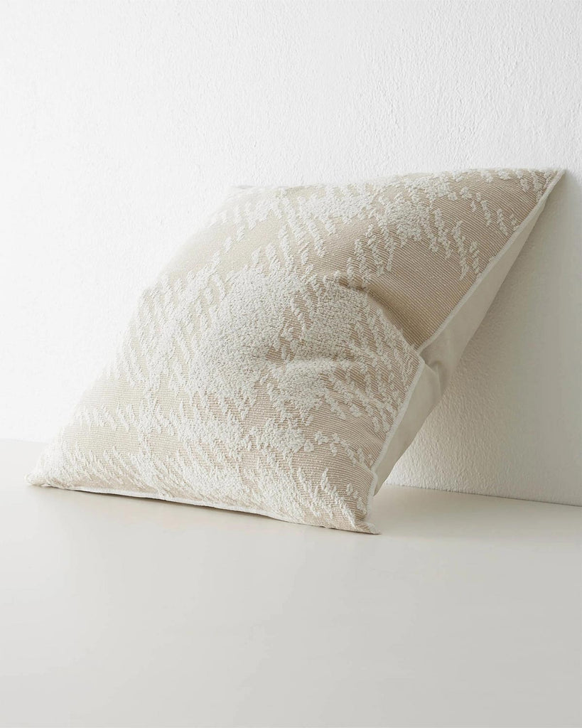 A side view of a light beige and cream cushion with a textured oversize check pattern.