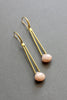 David Aubrey Peachy pink moonstone dangle earrigns with gold plated hooks and brass tubes, seen flat in perspective