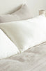 Close up of silk pillowcases in pearl white, by Bianca Lorenne, shown on a made bed