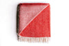 100% wool NZ throw blanket by Ruanui Station, in vibrant 'Rakaia red', with a corner folded