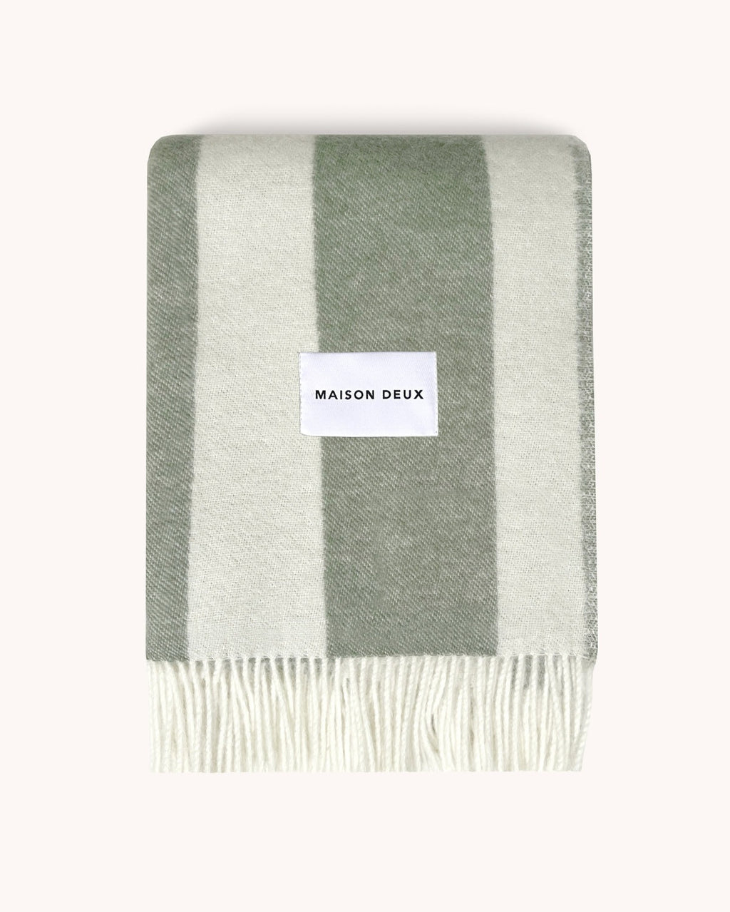 A folded, soft green and sage woolen throw by Maison Deux