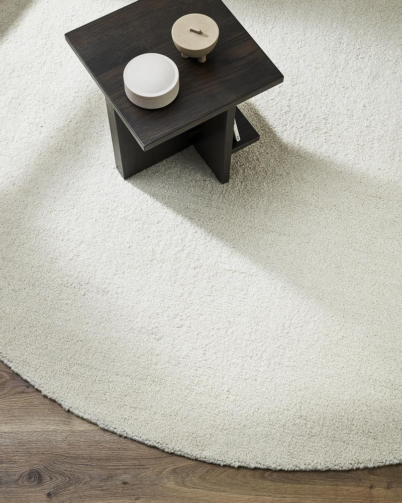The round, Dorset, boucle weave wool and merino floor rug by Baya in a natural white seen from above in a modern living room