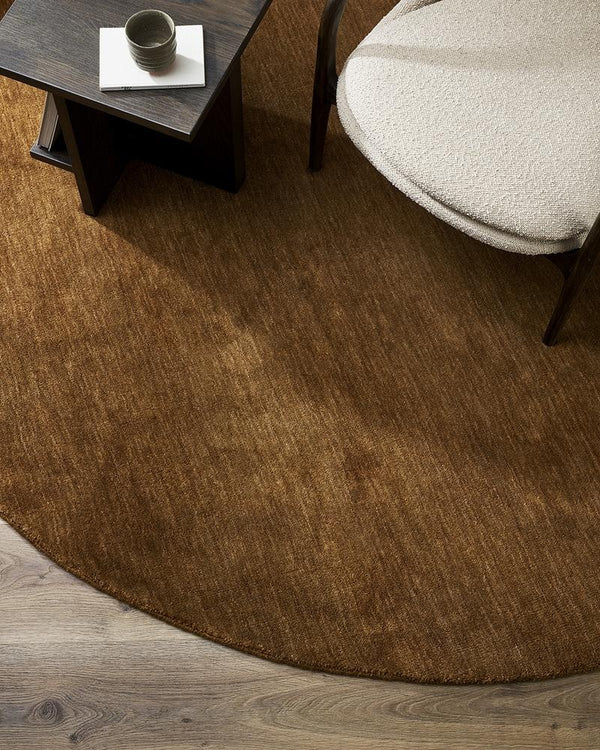 A lounge seen from above with a round, red-brown 100% wool floor rug. 