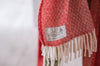 Close up of label and fringe detail of the pure wool NZ throw blanket by Ruanui Station, in vibrant 'Rakaia red'