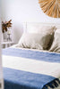 NZ wool throw blanket in blue nad white stripe, by Ruanui Station, seen on a bed