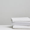 Three folded white 100% cotton bedding pieces stacked neatly on a white surface 