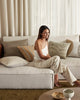 A stylish woman sitting on a couch in a modern living room amongst a beautiful selection of Weave Home cushions