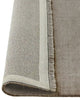 The Silvio wool floor rug, by Weave Home, in grey colour called 'Flint' seen rolled to reveal underneath