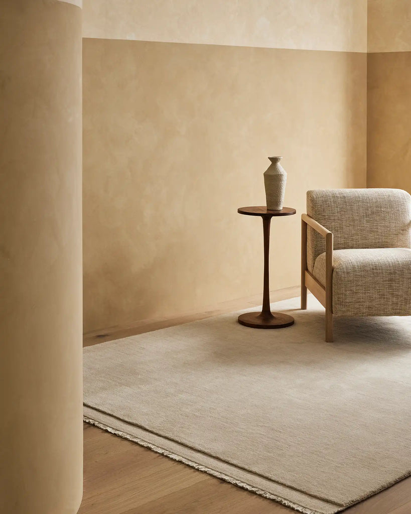 The Silvio wool floor rug, in a neutral creamy ecru colour, in a minimal living room
