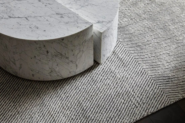 A charcoal and white patterned floor rug seen under a marble coffee table