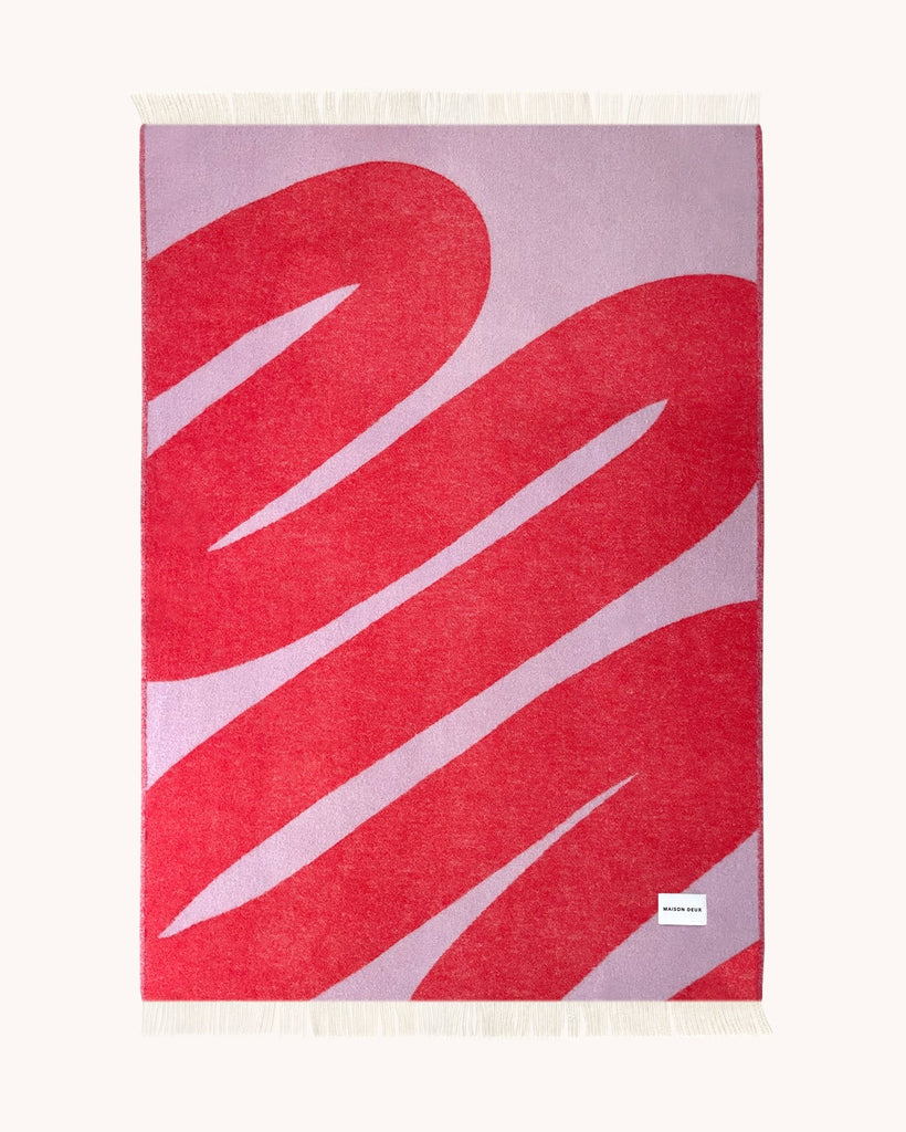 Full view of the Swirl patterned throw in shade Scarlet Lilac, the backside with a reversed pattern by Maison Deux