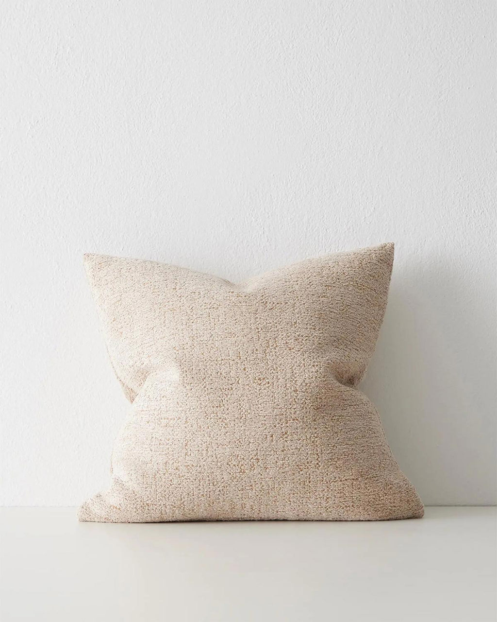 A textural cushion in a soft cream tone with warm brown highlighting.