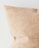 The corner of a textured cushion in soft clay tones. 