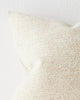 A close up image of an off-white warm toned cushion with a soft texture in the weave. 