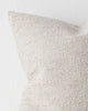 A detailed view of a cool toned cream cushion with soft textured detailing. 