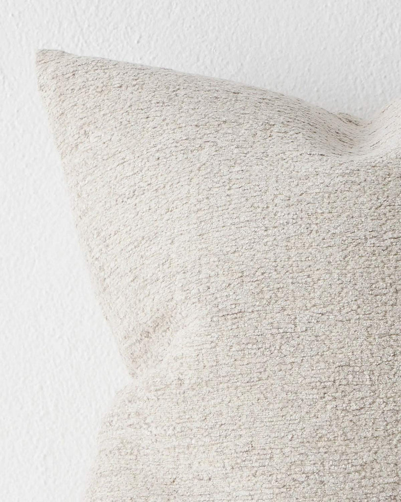 A detailed view of a cool toned cream cushion with soft textured detailing. 