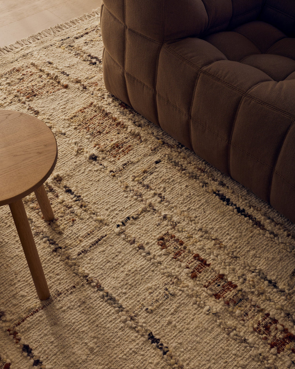 Close view of the Tribe Home Rama wool and jute rug in Cinnamon beside a sofa and side table
