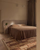 Tribe Home Rama wool and jute rug in Sienna beside a bed in a bedroom