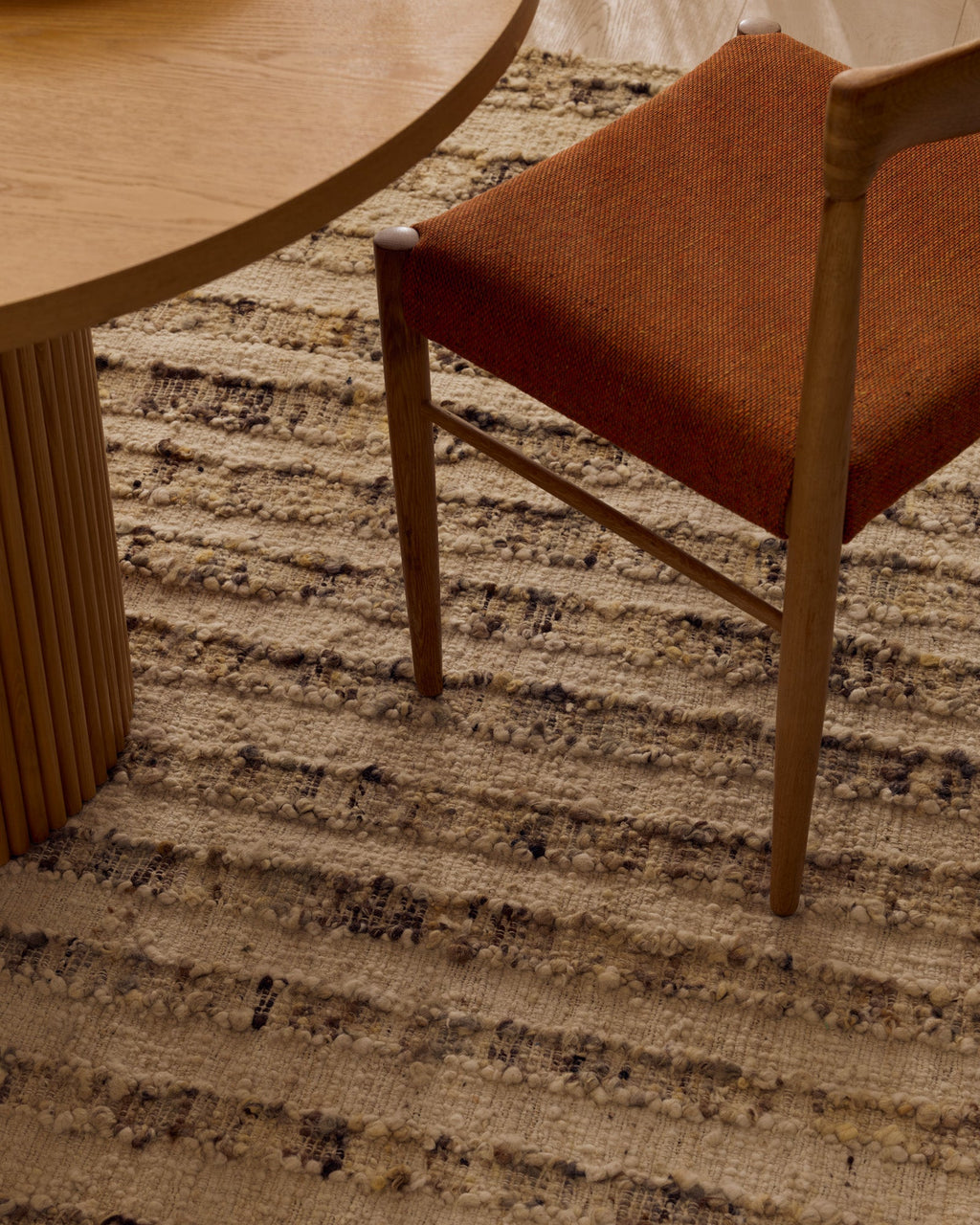 Close view of the Tribe Home Tulsi wool and jute rug in Caraway beneath a dining chair