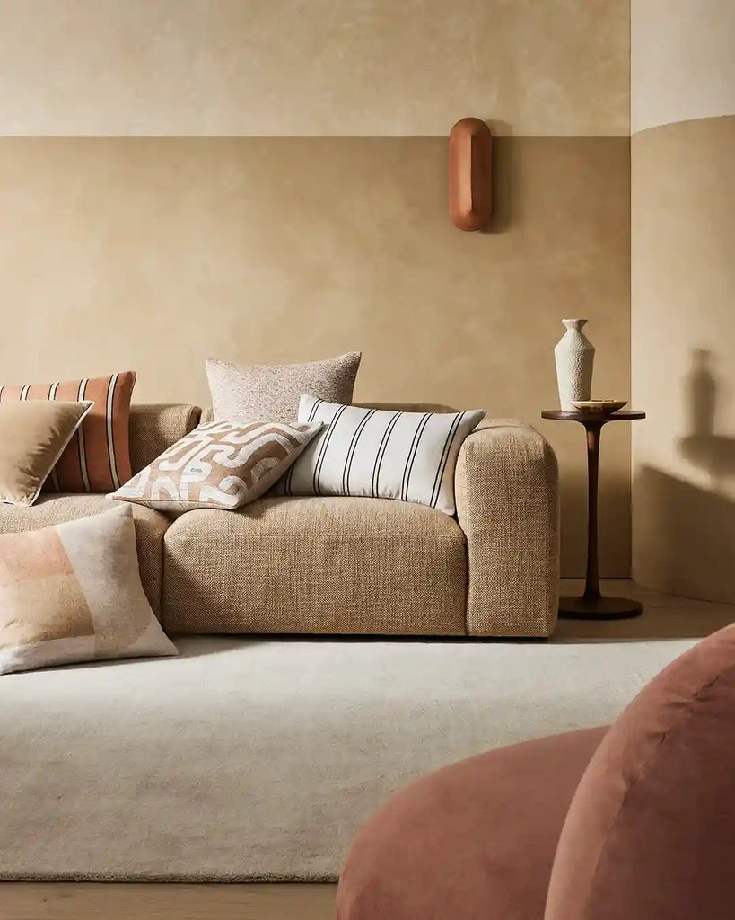 A warm brown and coral coloured living room featuring stylish cushions by Weave Home