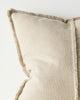 Close up of a beige cushion with textured trim on a light background