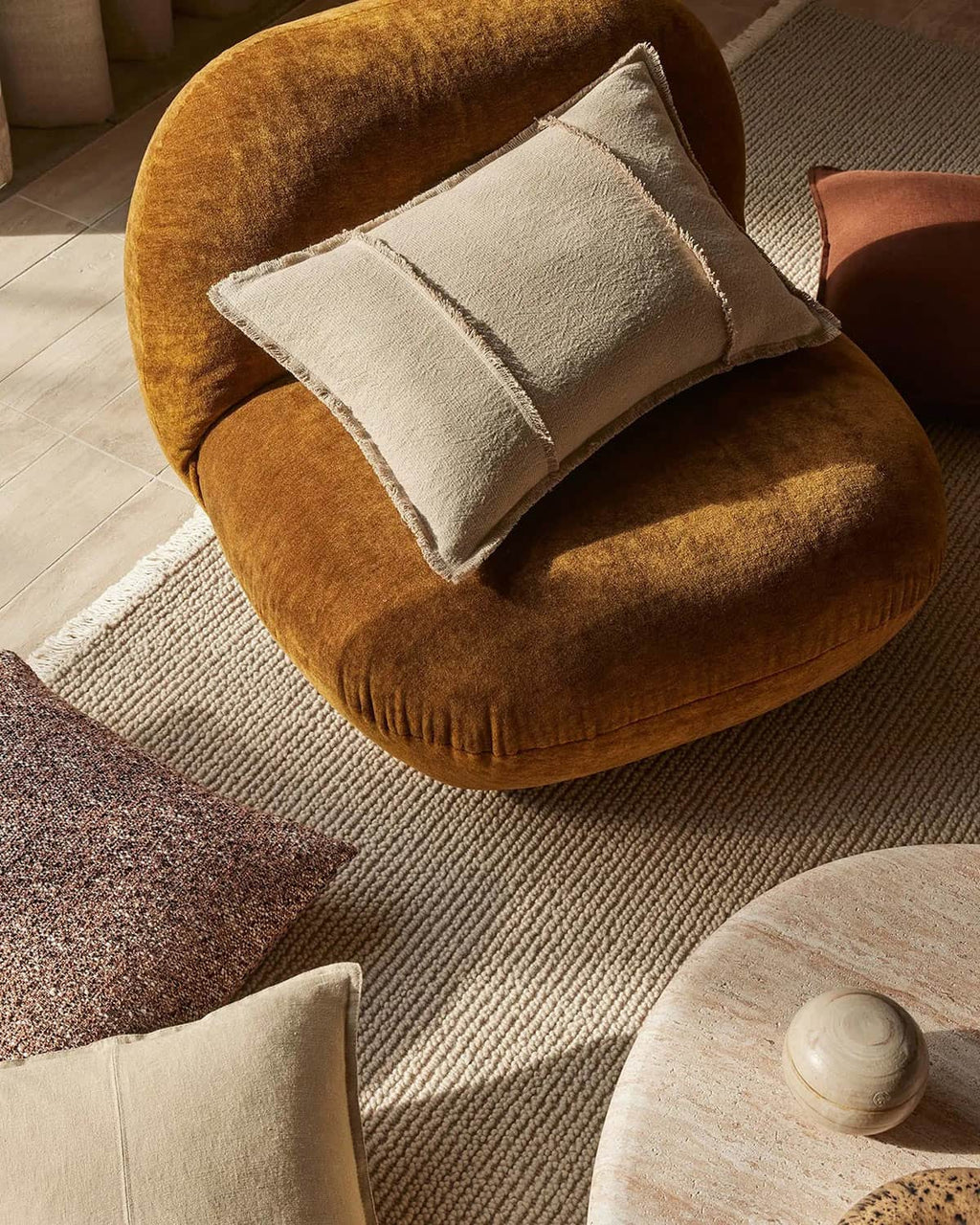 Round brown chair with a beige pillow on a textured beige rug