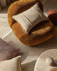 Round brown chair with a beige pillow on a textured beige rug