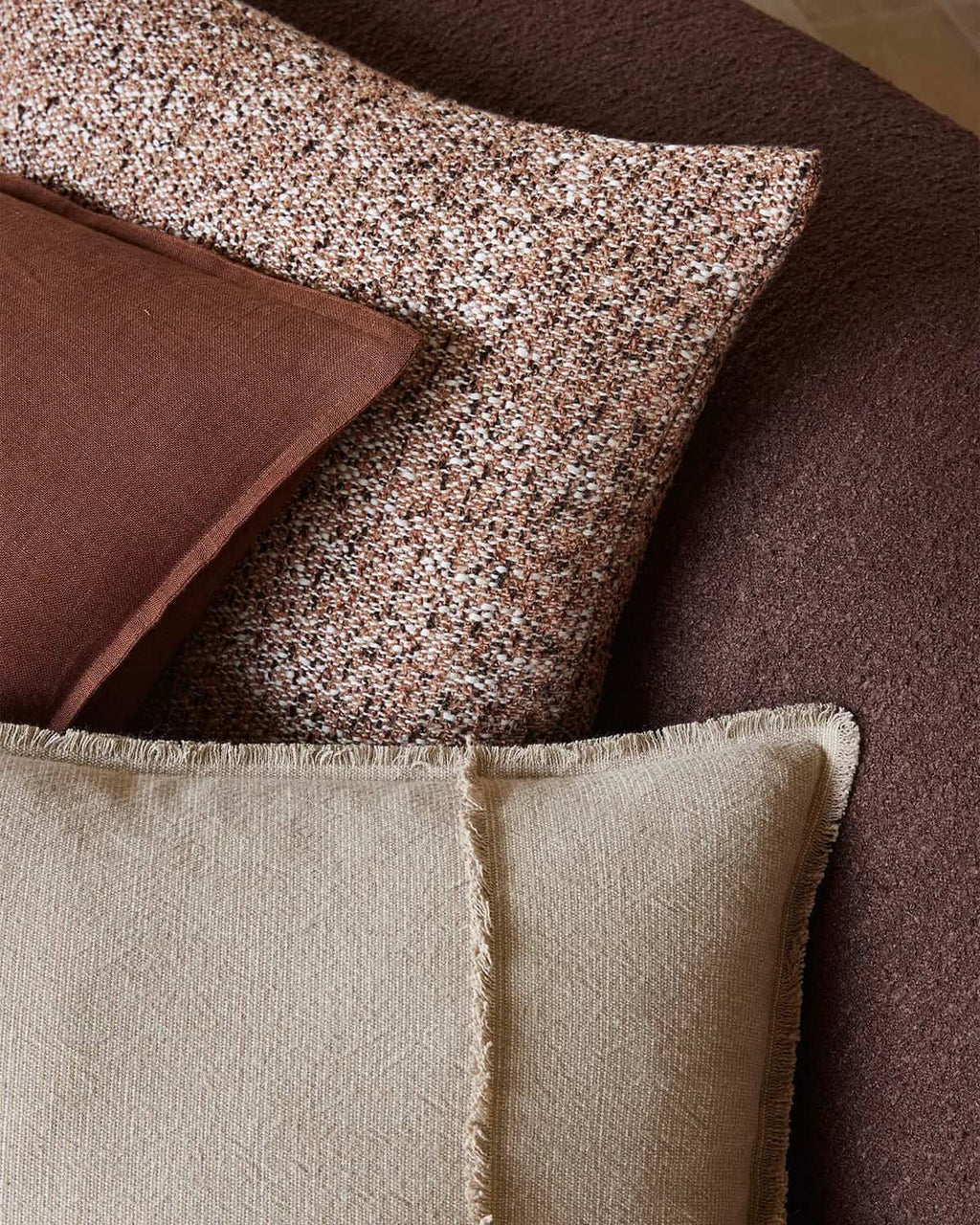 Close-up of textured pillows in brown and beige on a sofa.