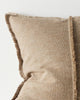 Close-up of a textured beige pillow with frayed edges on a light background