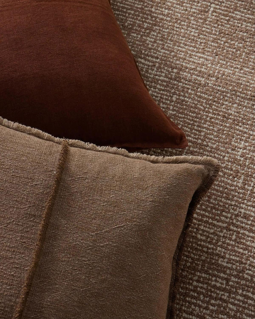Close-up of two brown textured pillows on a textured surface.