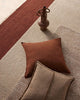 Brown pillows and beige rug with a decorative vase.