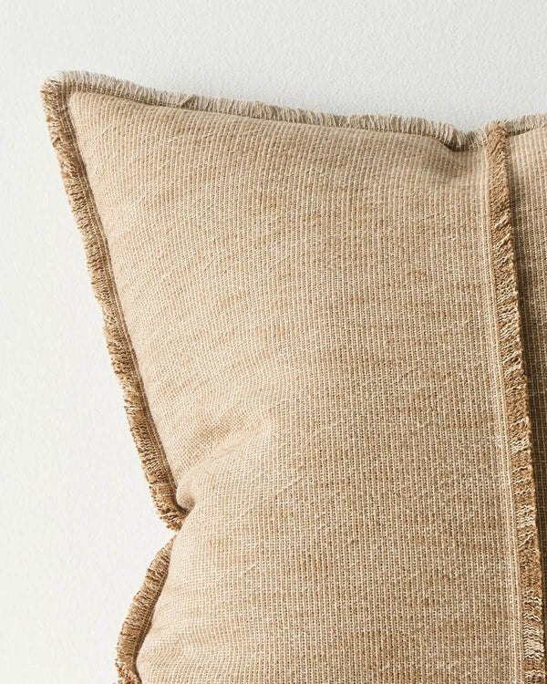 Close up of a warm beige cushion with textured edge on a light background