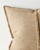 Close up of a warm beige cushion with textured edge on a light background