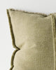 Corner of a textured green cushion with frayed edges on a light background