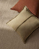 Green pillow on a textured surface with a brown pillow in the background