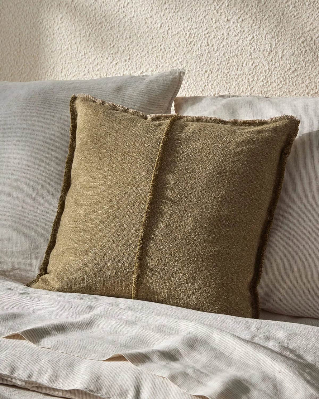 Two textured pillows on a light-colored bed against a neutral wall.