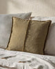 Two textured pillows on a light-colored bed against a neutral wall.