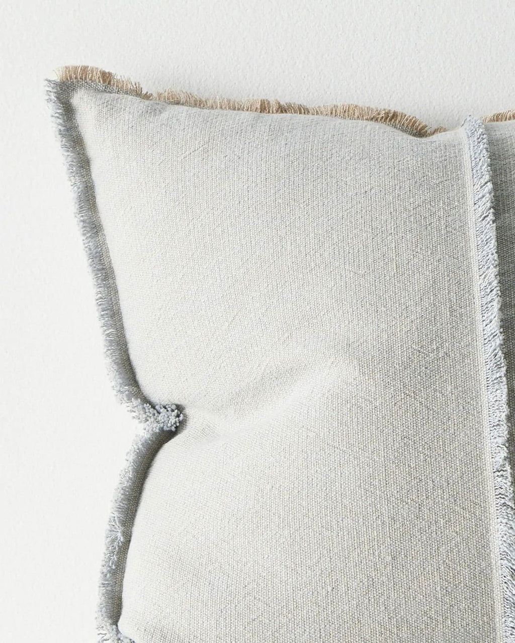 Textured pillow with frayed edges on a light background