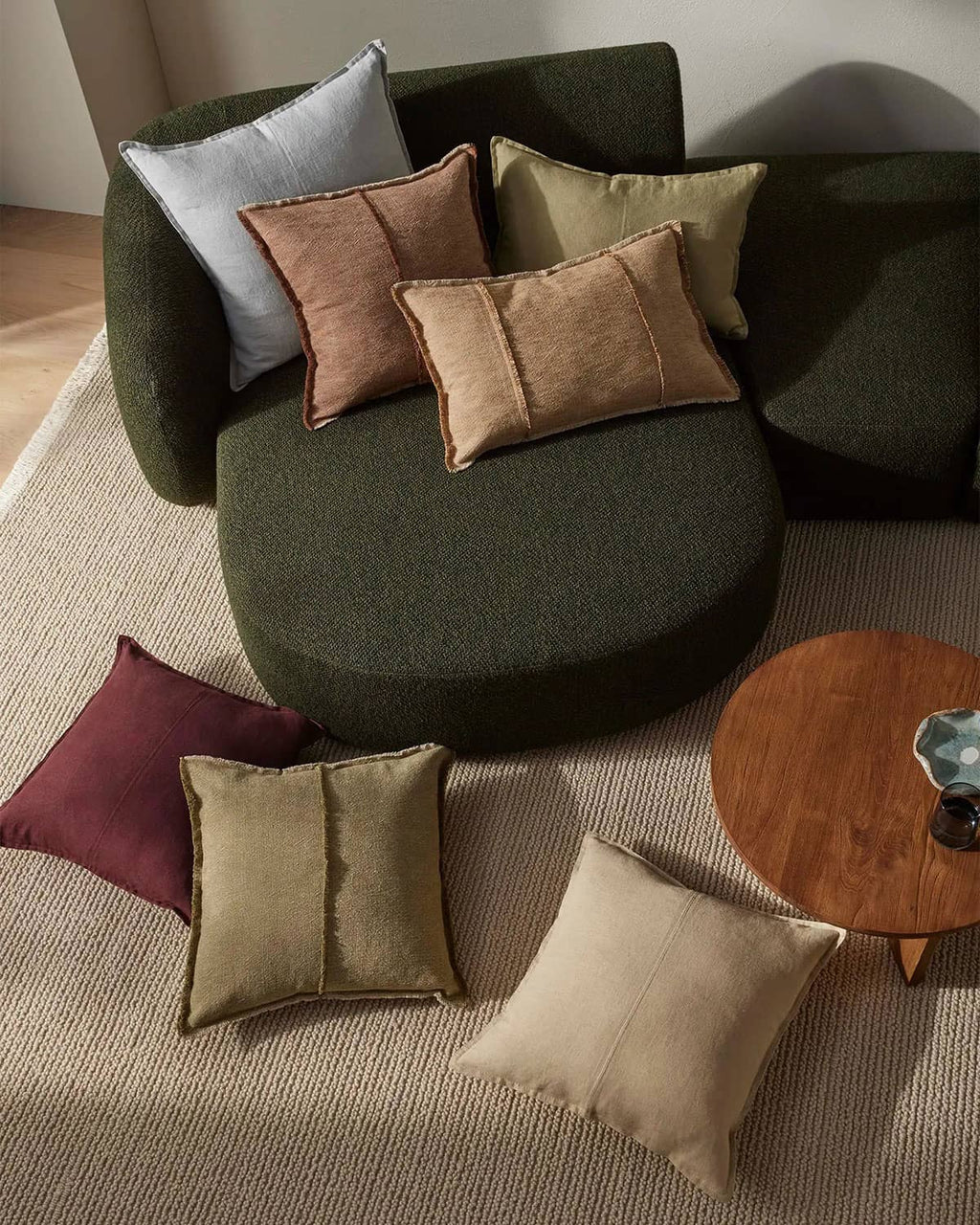 Green sofa with various colored cushions in a living room setting.
