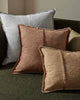 Three textured pillows in brown and gray on a green sofa.