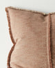 Close-up of a brown textured pillow with frayed edges on a light background