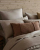 Neatly arranged pillows on a bed with a textured wall in the background