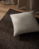 Beige pillow on a textured brown floor rug