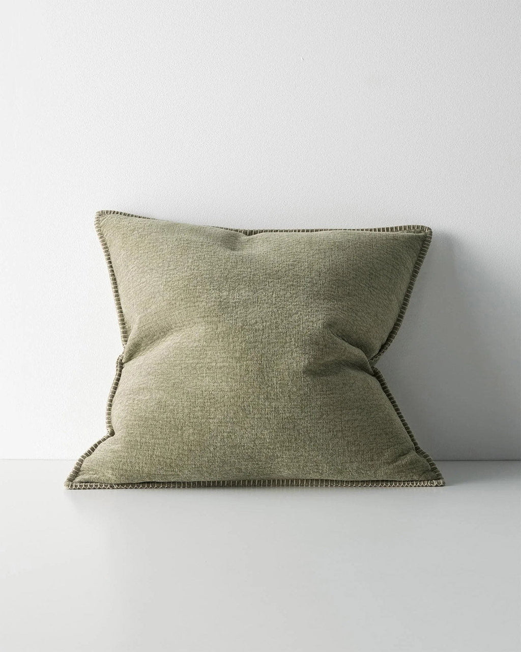 Green cushion with a stitch detail, on a white background