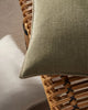 Close-up of a textured green cushion by Weave Home on a woven wooden chair.