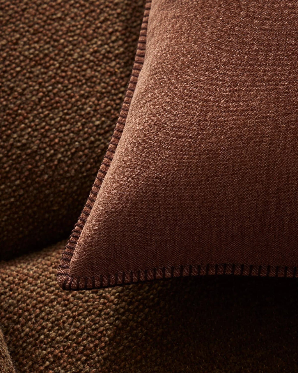 Close-up of a brown textured cushion with elegant stitching on a brown couch
