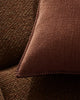 Close-up of a brown textured cushion with elegant stitching on a brown couch