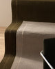 Two NZ wool rugs by Weave laid out on stairs with the corner of a chair