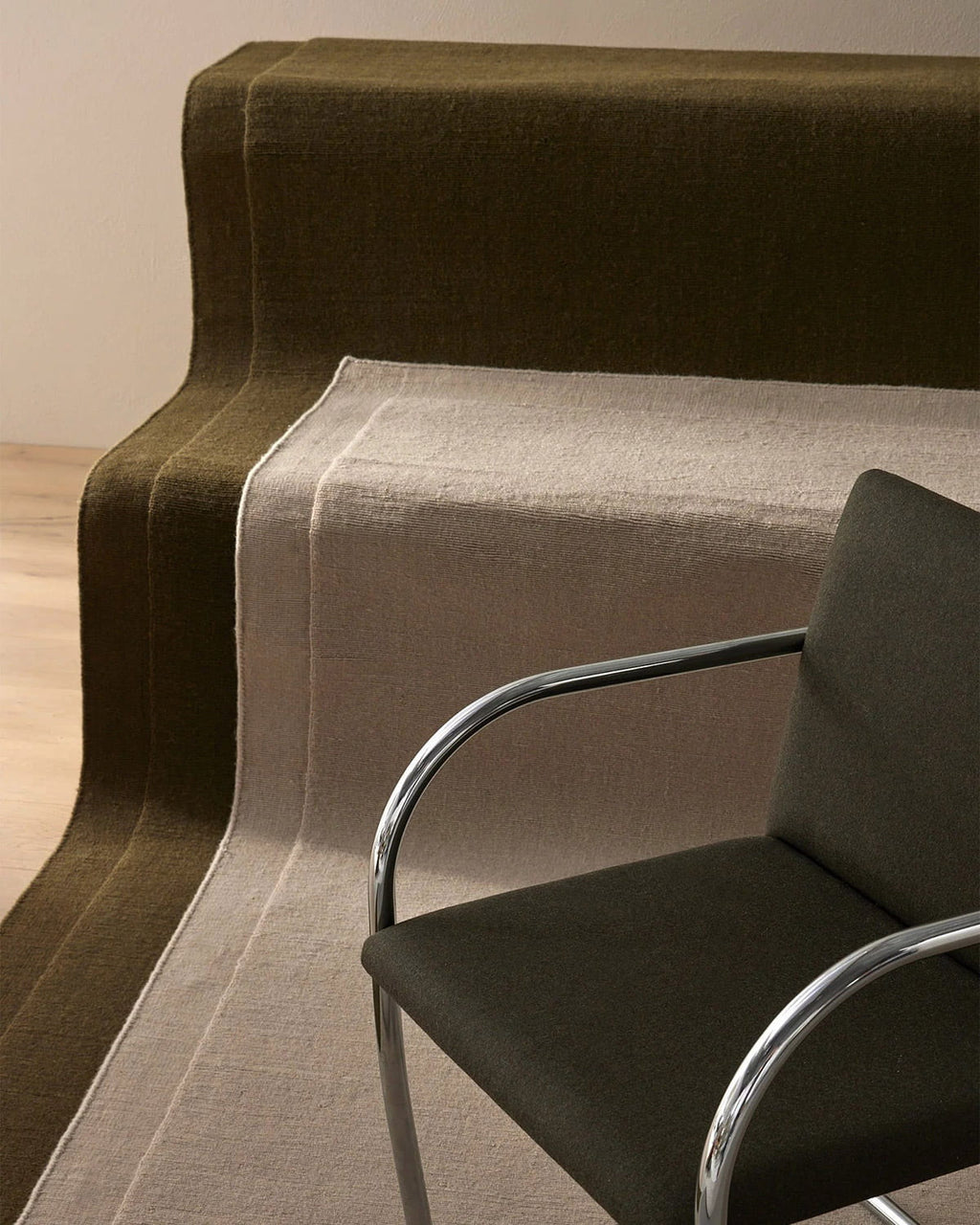 Two NZ wool rugs by Weave laid out on stairs with a brown chair in front