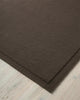 A close up corner of  Chocolate brown NZ wool floor rug with cut border, by Weave Home